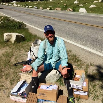 Mountain Man sitting on a pile of care packages