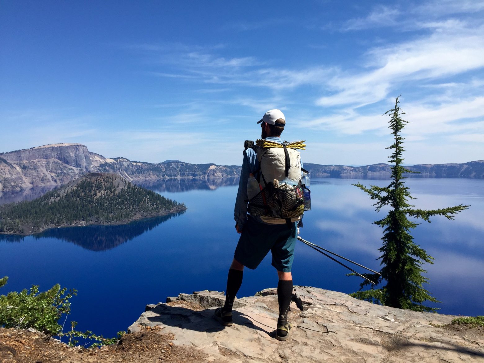 Mountain Man looking out over Crater Lake as it perfectly reflects the sky