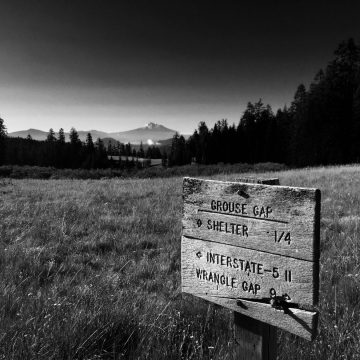 PCT sign with trail mileages and Mount Shasta in the distance