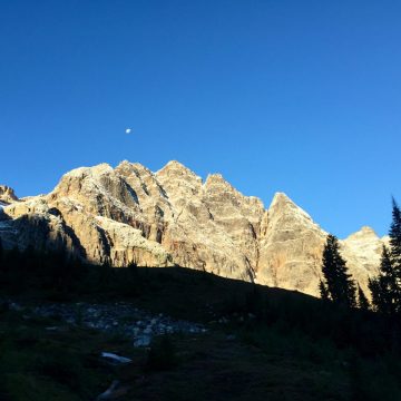 Blue sky behind jagged peak lit by the morning sun