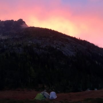 Pink and purple sky as sun rises over a peak in the North Cascades