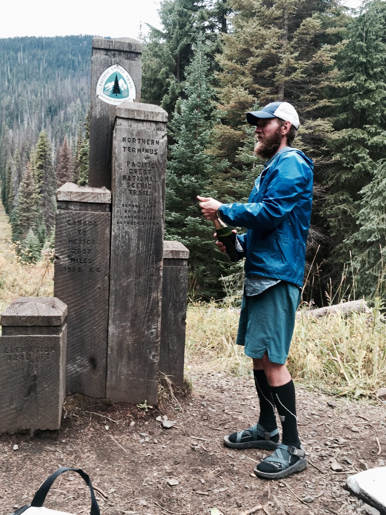 Mountain Man popping champagne at the PCT Northern Terminus